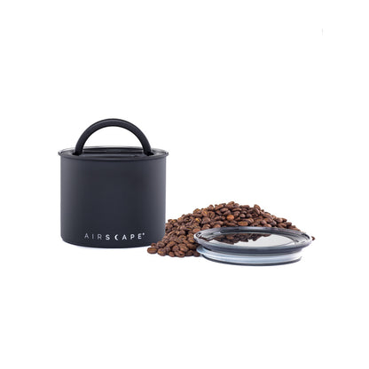 Black coffee storage container with lid and coffee beans on a white background