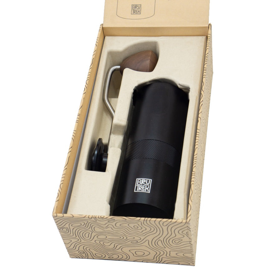 Black hand coffee grinder with wooden handle in a branded box on a white background