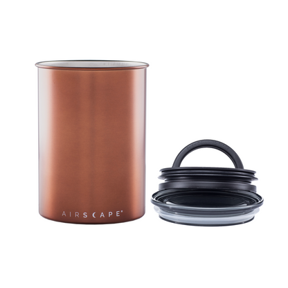 Copper-colored canister with black lid and clear lid on a white background