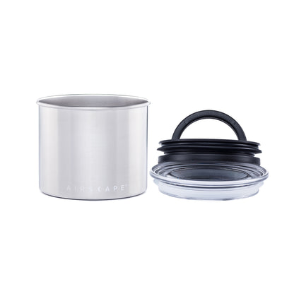 Stainless steel container with black lid on a white background