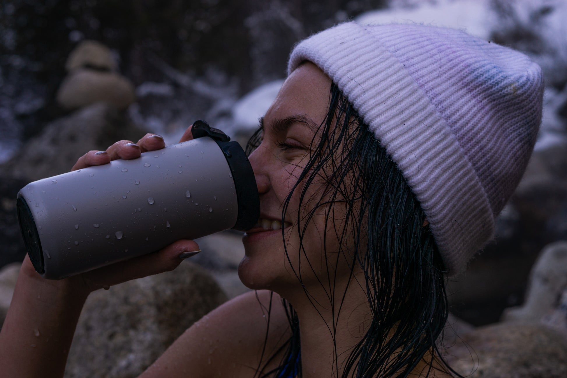 Person drinking from a insulated mug outdoors in a snowy setting