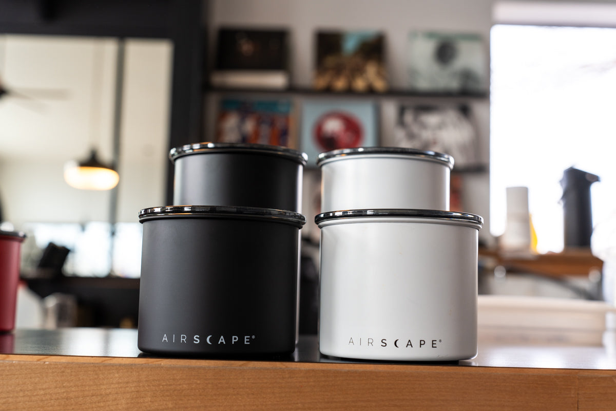 Four AIRSCAPE containers in black and white on a kitchen counter.